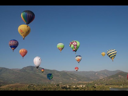 Hot air balloons in flight with mountains in the distance during summer in Park City, Utah. 