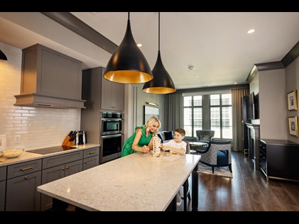 Mother and son playing Jenga in their suite kitchen at Liberty Place Charleston by Hilton Club in Charleston, South Carolina. 