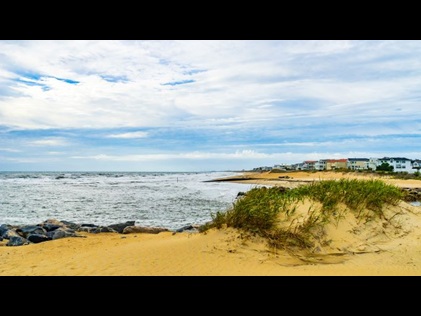 Golden sand dunes with ocean waters and quaint coastal cottages in the distance, Grommet Island Park, Virginia Beach, Virginia.