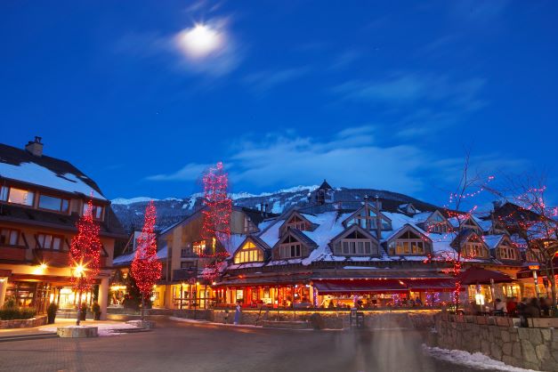 Whistler, Canada, main street, glowing, snow-capped mountains in the distance.