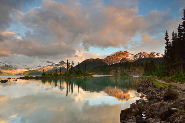Peaceful mountain lake during summertime, sunset painted skies overhead, Whistler, Canada.