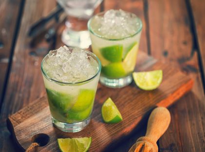 Two cocktails in clear glasses with ice and limes