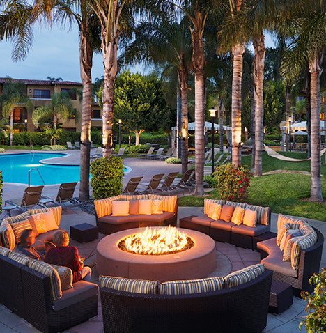 A firepit surrounded by seats with a view of the ocean.